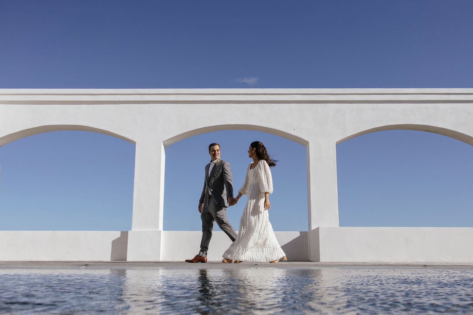 Pareja caminando frente a arcos blancos
