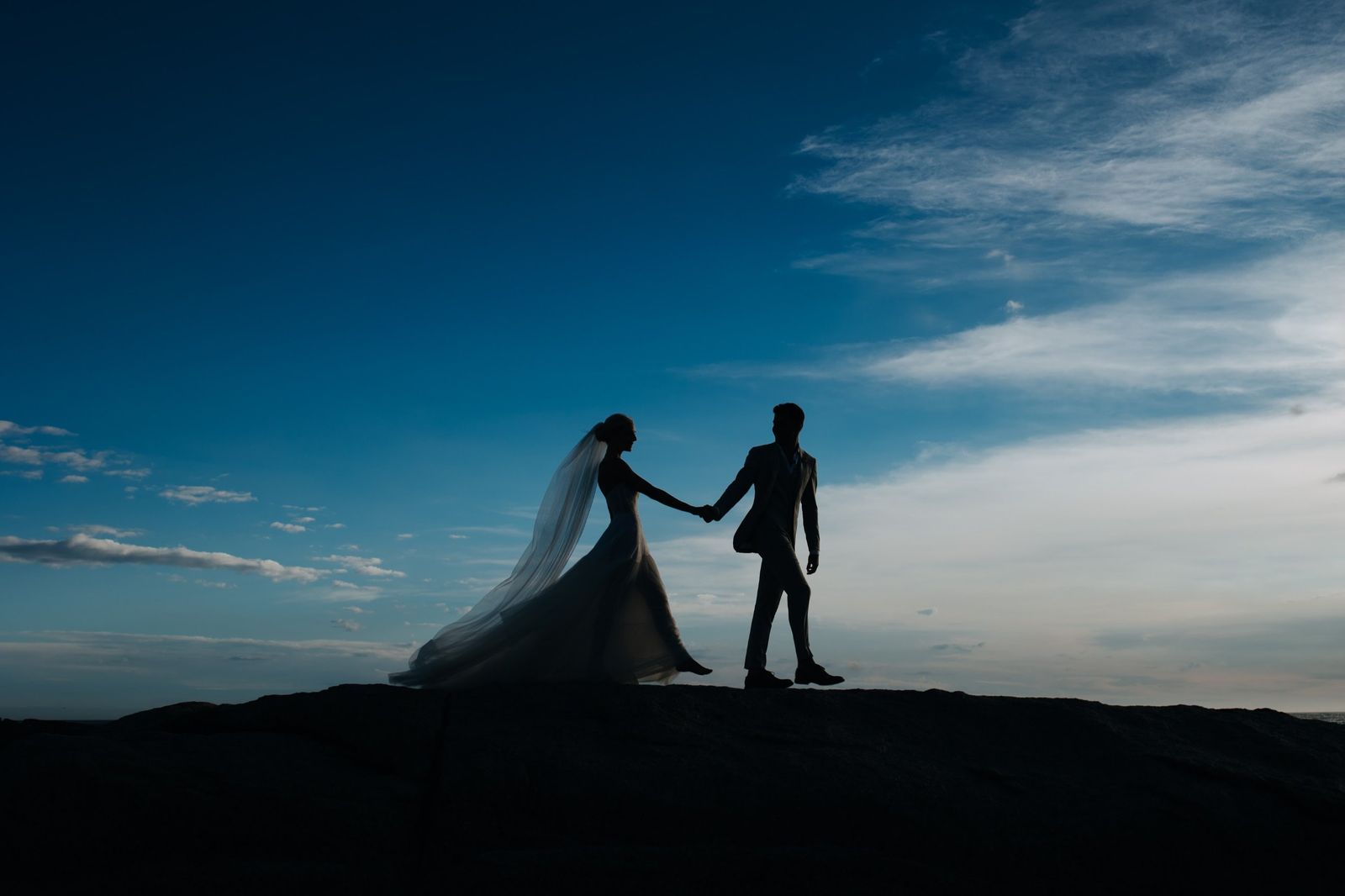 Silueta de los novios caminando de la mano bajo el cielo azul