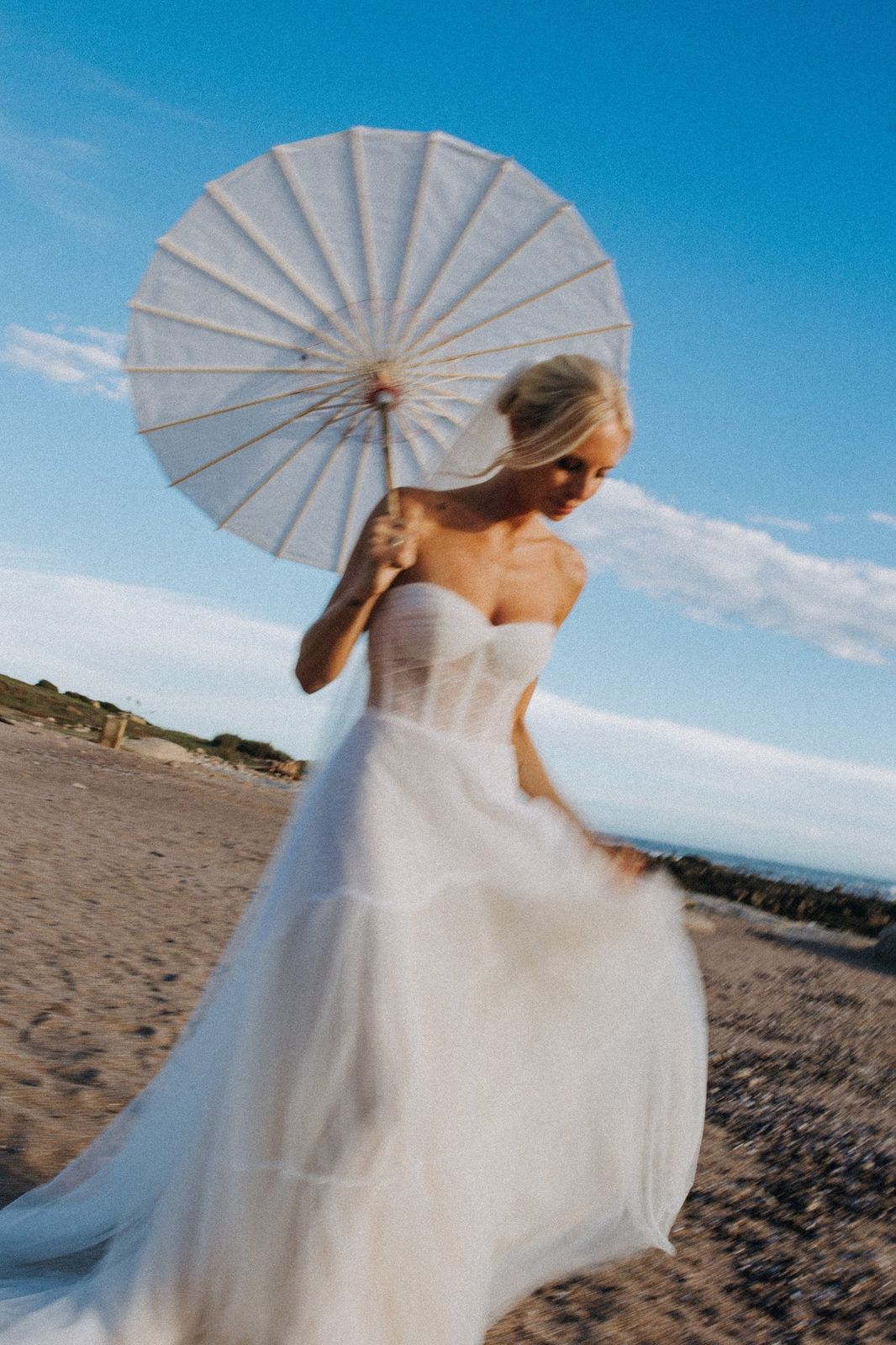 Novia con sombrilla de papel en la playa